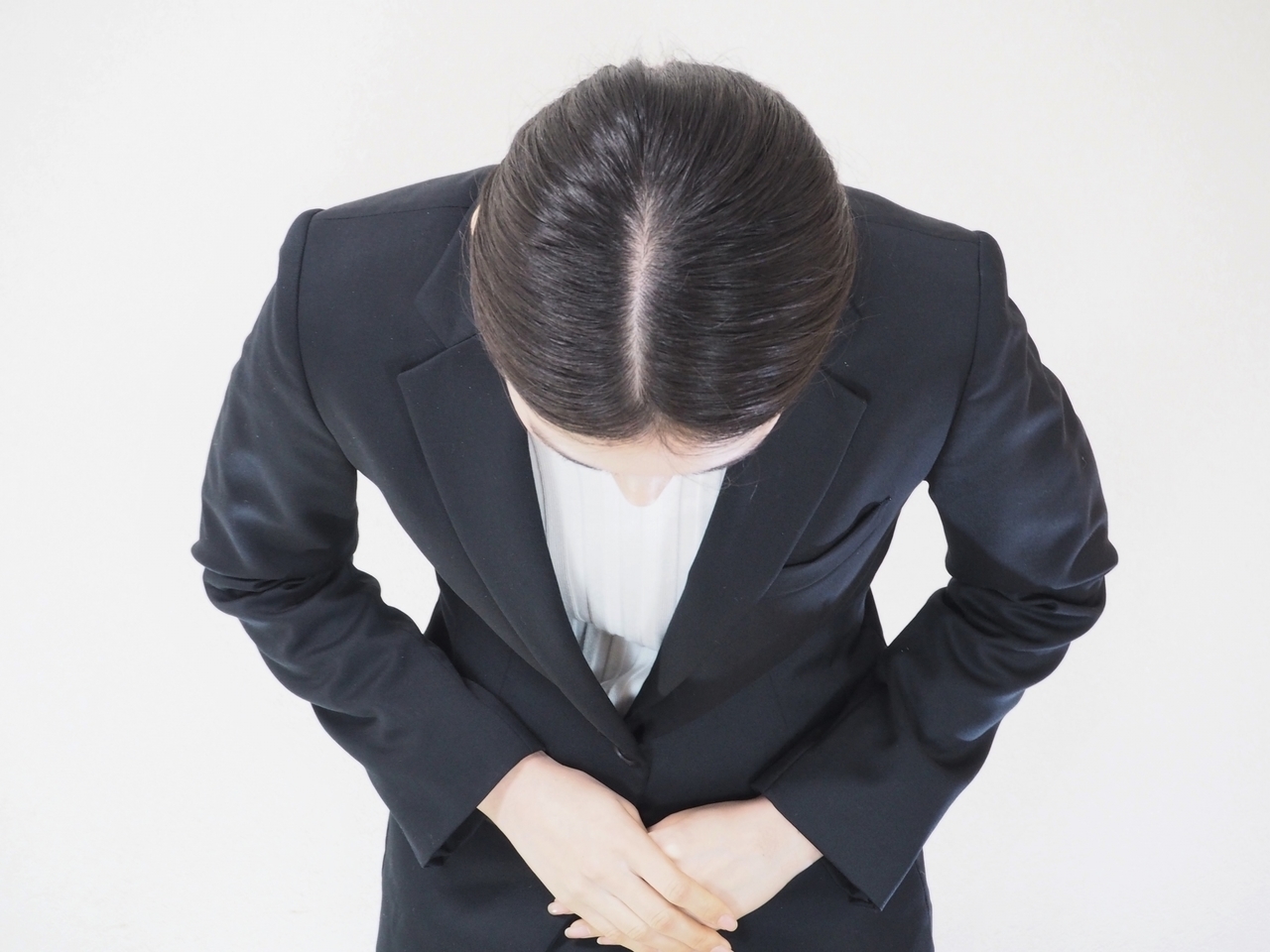 頭を下げて深くお辞儀をするスーツを着た女性スタッフ